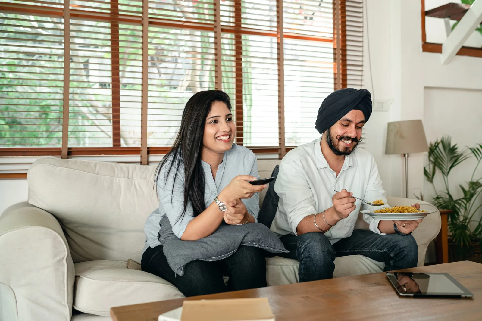 Couple sitting on a sofa with a TV remote
